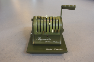 Alte grüne Kasse auf einem Betonboden mit ein paar Gegenständen im Hintergrund.