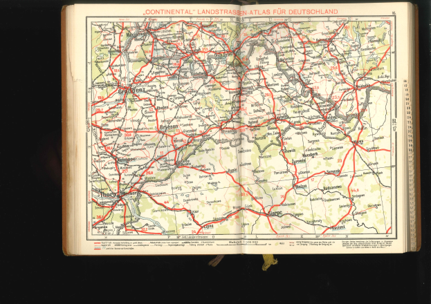 Offenes Buch mit einer detaillierten Karte von Deutschlands Straßen und Autobahnen auf einem schwarzen Hintergrund.