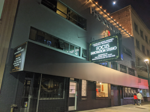 Außenansicht des Focus Innovation Studio in New York City bei Nacht, mit beleuchteten Gebäuden, Menschen auf dem Gehweg und dem Nachthimmel.