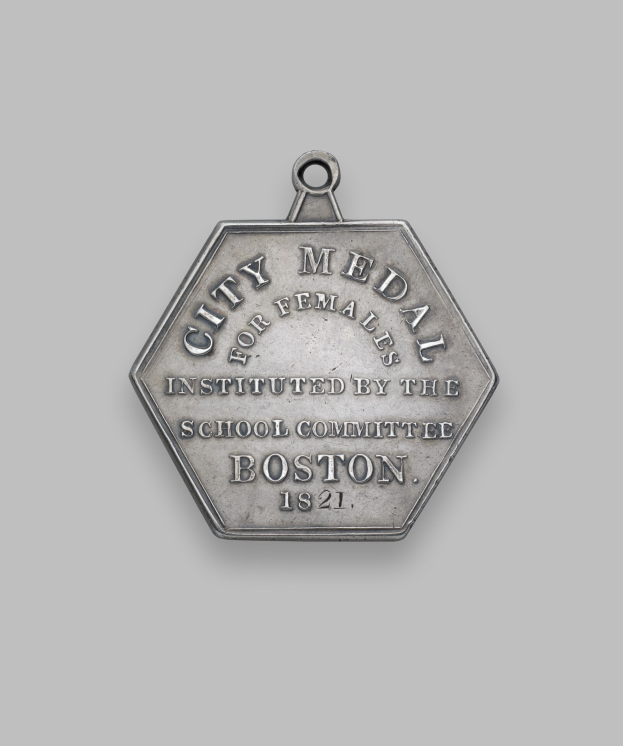 Eine silberne Medaille mit der Aufschrift 'Stadtmedaille für Frauen' vor einem weißen Hintergrund.