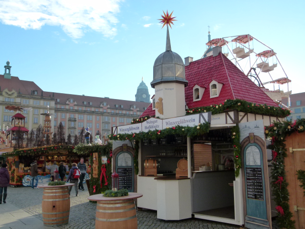 Ein pulsierender Weihnachtsmarkt in Nürnberg, Deutschland mit Menschen um geschmückte Stände, festliche Lichter, ein Riesenrad im Hintergrund und eine Tafel mit Text auf der rechten Seite.