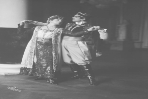 Schwarzes und weißes Foto eines Mannes und einer Frau, die in einem Ballsaal tanzen, mit einer Säule und einer Wand im Hintergrund; der Mann trägt Schuhe, was darauf hindeutet, dass sie eine Vorstellung geben.