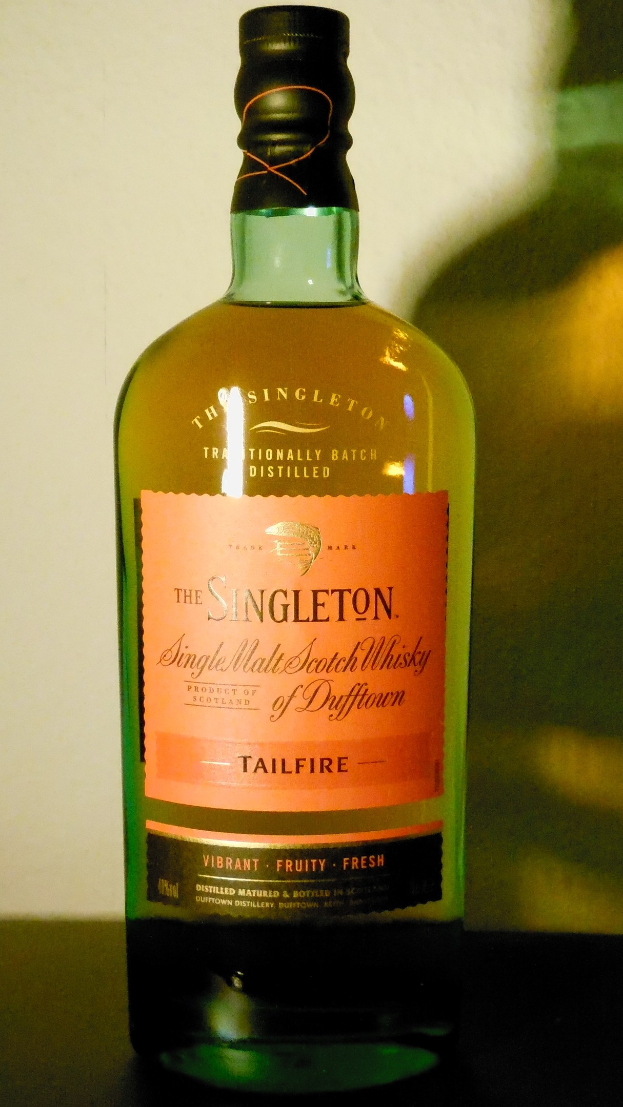 Eine tiefe Bernsteinflasche Singleton of Dufftown Tailfire Single Malt Scotch Whisky mit einem schwarzen Etikett, das eine Löwenkrone und ein Schloss zeigt.