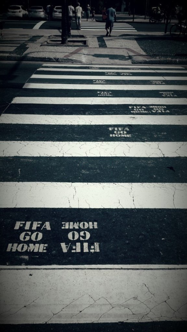 Menschen auf einem Zebrastreifen mit sichtbaren Autos in der linken oberen Ecke.