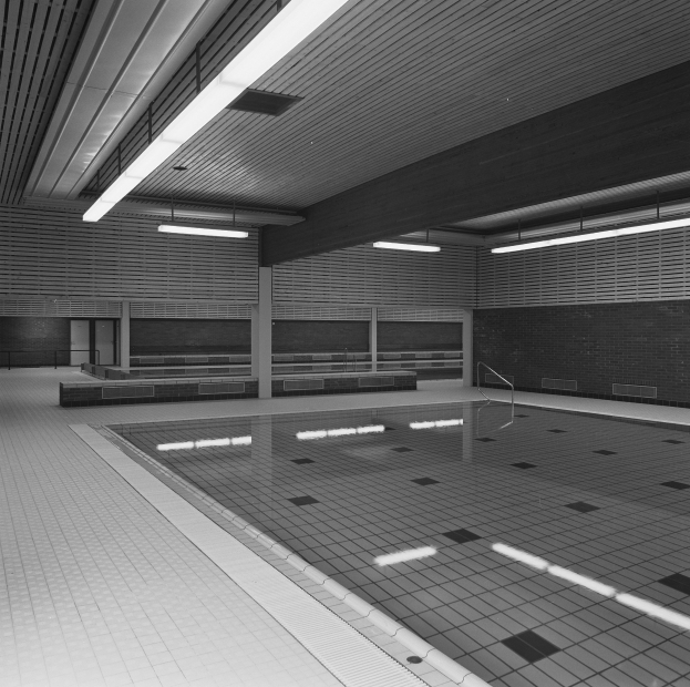 Innenpool mit klarem Wasser, gefliestem Boden, Wänden und Deckenleuchten, umgeben von ein paar Gegenständen in einer ruhigen Umgebung.