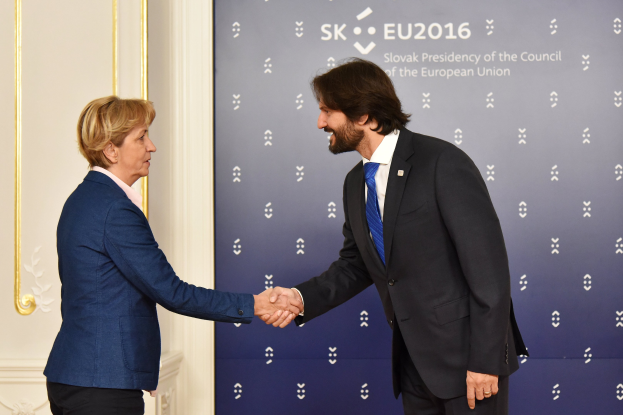 Bundeskanzlerin Angela Merkel und Bundeskanzler Joachim Gauck schütteln Hände vor einem "EU-Gipfel"-Plakat und lächeln freundlich.