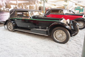 Eine Gruppe von Oldtimern in einem Museum ausgestellt, mit einem Banner auf der linken Seite mit Fotos von Menschen und Text und an der Decke angebrachten Lichtern im Hintergrund.