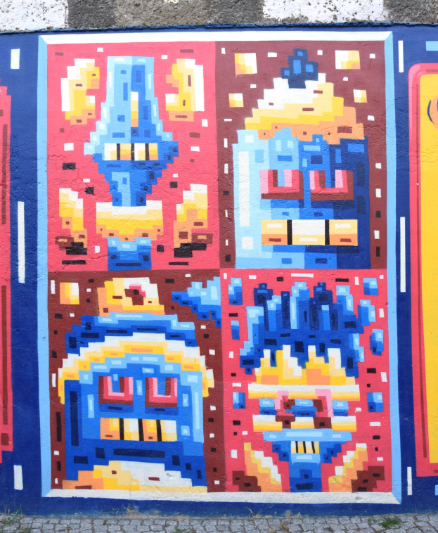 Ein leuchtendes, farbenfrohes Wandgemälde mit verschiedenen Formen, das die Seite eines Gebäudes in Berlin, Deutschland, bedeckt.