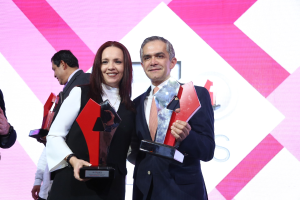 Zwei Personen, die strahlend lächeln und Trophäen halten, bei einer Preisverleihung