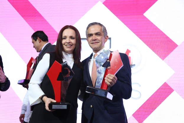 Zwei Personen, die strahlend lächeln und Trophäen halten, bei einer Preisverleihung