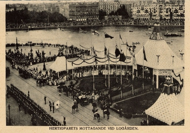 Schwarze und weiße Fotografie einer Menschenmenge bei einem Karneval mit Zelten, Fahnen, Stangen, Pferden, Gebäuden, Bäumen und Wasser im Hintergrund, mit Text am unteren Rand.