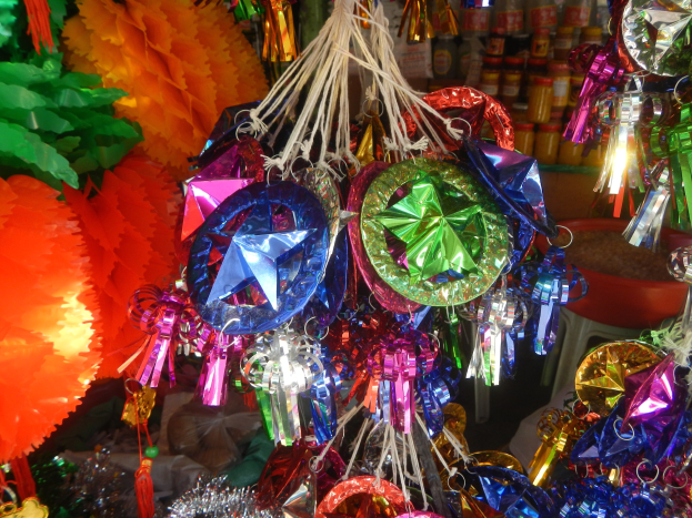 Farbenfrohe Festschmuck wie Laternen, Bänder und andere Gegenstände hängen von der Decke über Regalen mit Flaschen in einer feierlichen Atmosphäre.