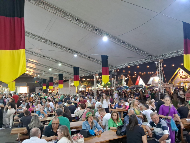 Große Gruppe von Menschen an Tischen unter einem Zelt auf dem Oktoberfest in München, Deutschland, mit festlichen Décor im Hintergrund.