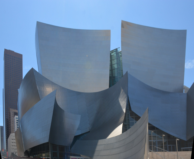 Modernes gläsernes Konzerthaus mit Treppen und Geländern, die zum Eingang führen, umgeben von Menschen, anderen Gebäuden und einem klaren blauen Himmel in Los Angeles.