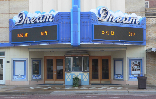 Außenansicht des Dream Theaters in St. Louis, Missouri, mit Glastüren, Fenstern, einem Namensschild, einem Mülleimer, einem Topf mit einer Pflanze und einer Straße unten.