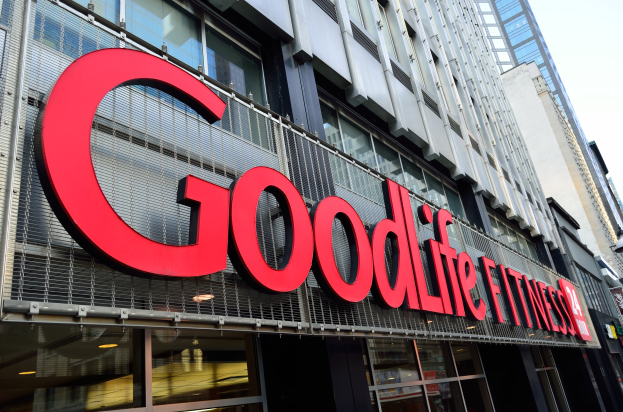 Ein Goodlife Fitness Studio in New York City mit Glaswänden und einer Namensplakette, umgeben von anderen Gebäuden unter einem sichtbaren Himmel.