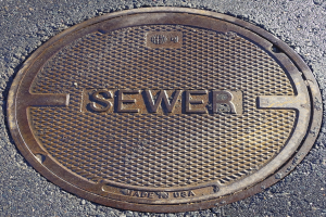 Metallschachtdruckgussdeckel auf der Straße mit der geprägten Aufschrift "Kanal"