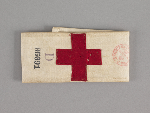 Erste-Hilfe-Kasten mit rotem Kreuzsymbol auf einem Stoffbeutel, der auf einer Oberfläche liegt.