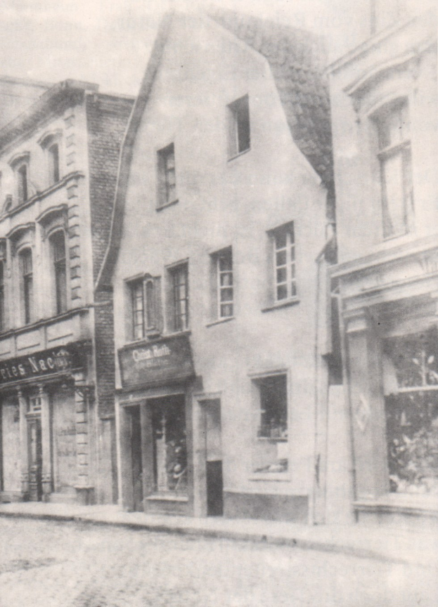 Schwarz-weiß-Bild einer Straße mit Gebäuden mit Fenstern und Schildern, darunter eine Straße.